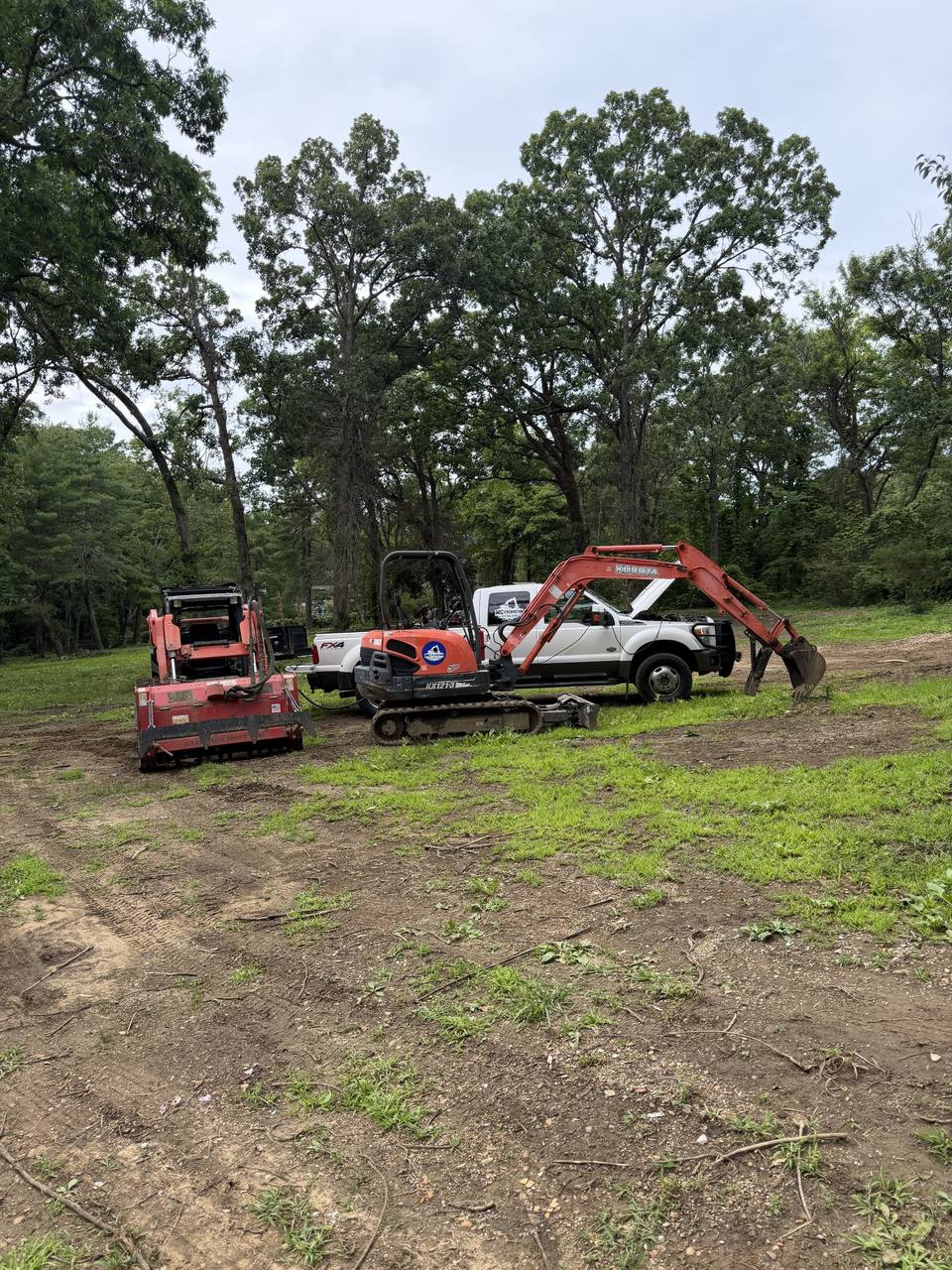 Excavator, mulcher and truck on a cleared lot