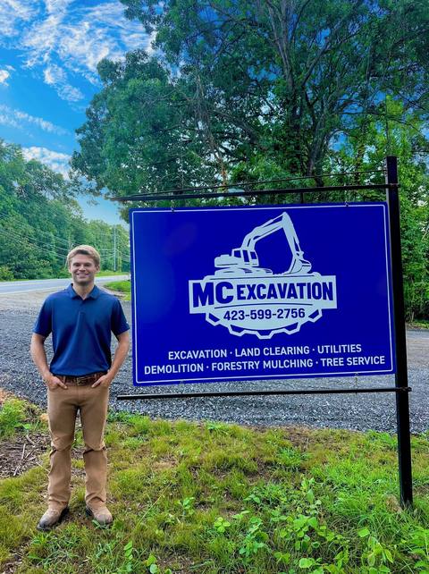 The owner standing next to the MC Excavation sign