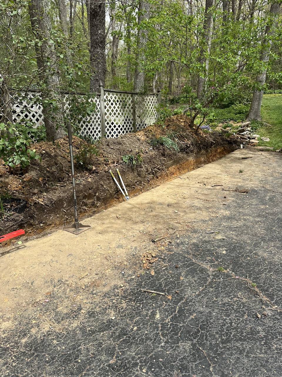 Trench cut along a driveway for a retaining wall base