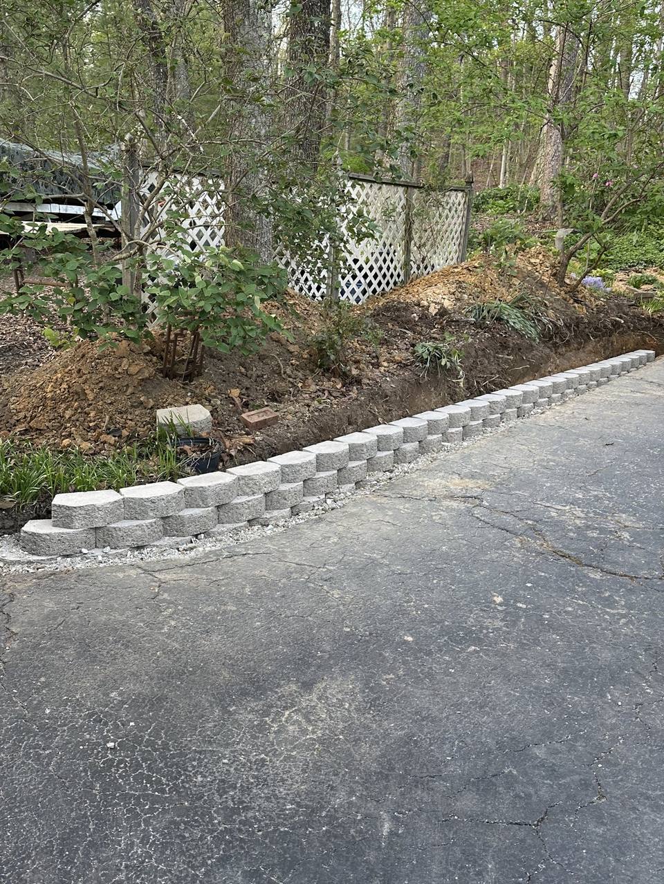 Block retaining wall going up along a drive, the bank cut behind it