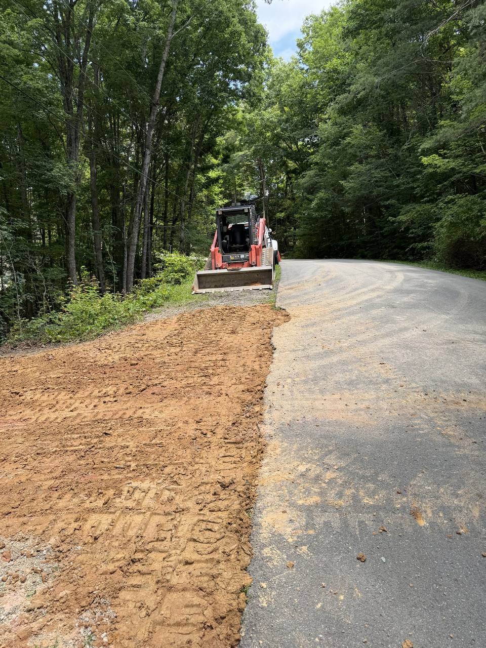 Loader spreading base along a paved drive